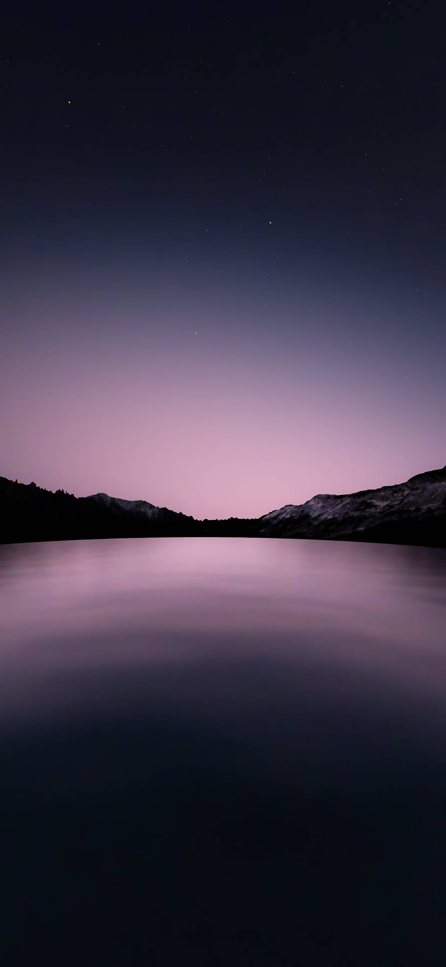 平靜的湖面倒映著紫色的暮色天空和星空下的山巒剪影