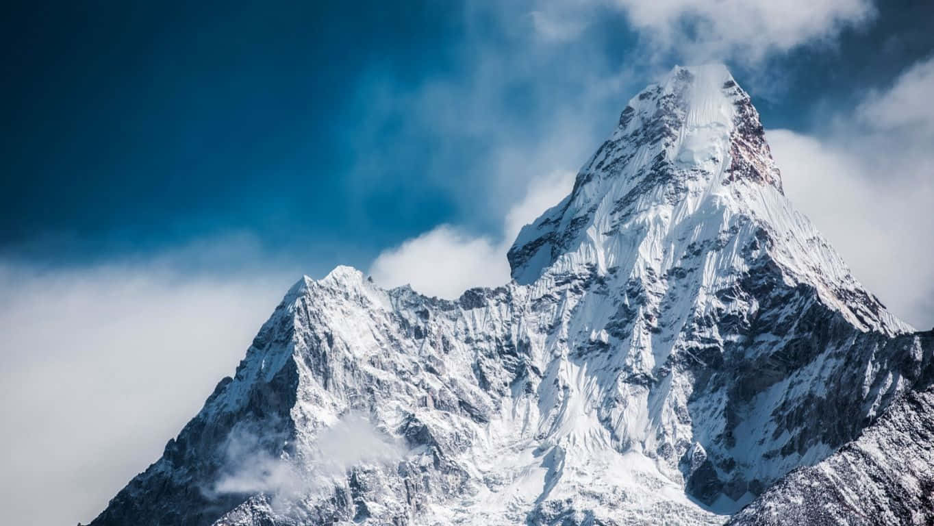 雪山峰頂聳立於雲層之上，藍天背景