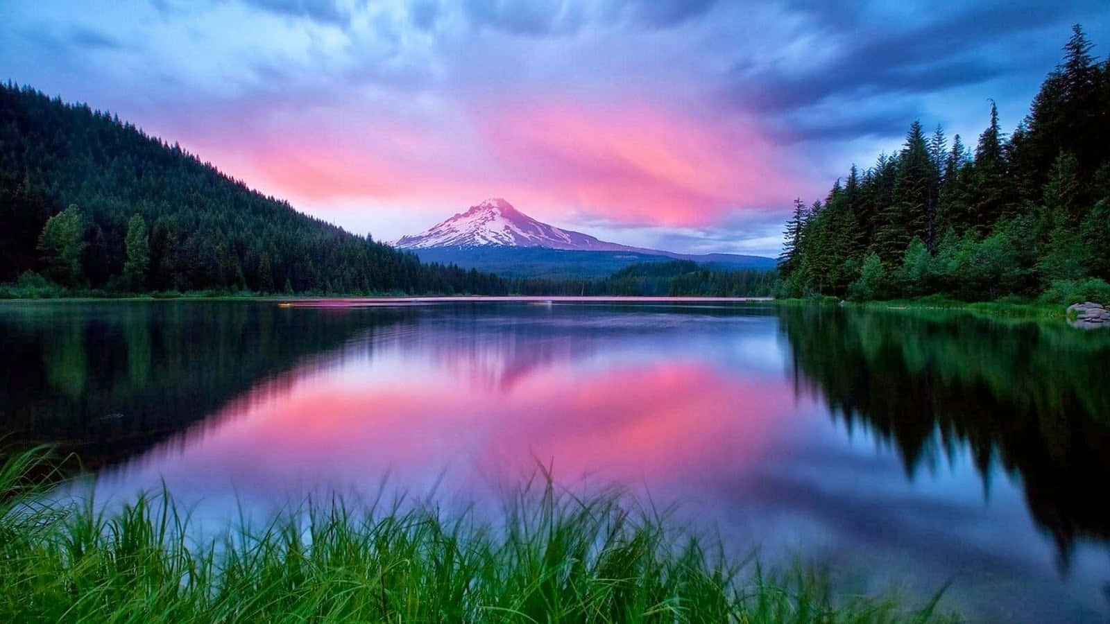湖面夕照倒影奇景 壁紙 — 一座積雪的山峰倒映在平靜的湖面上，粉紅色和紫色的雲彩在日落時分發光。