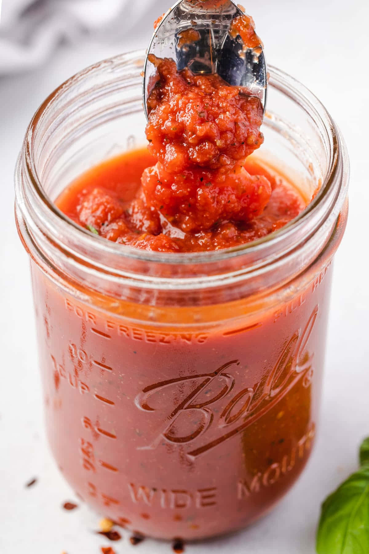 Red Sauce 桌布 壁紙 — 湯匙從玻璃Ball梅森罐中舀起濃稠的紅色番茄醬，旁邊有新鮮羅勒。