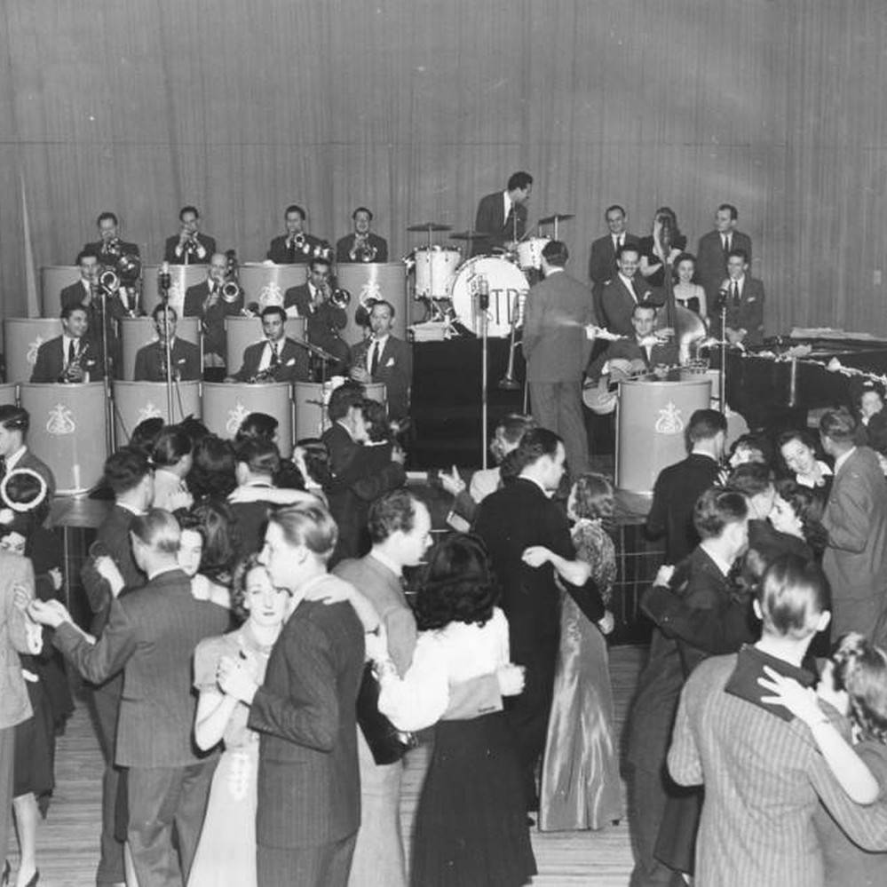 湯米·多西與樂隊於帕拉迪姆音樂廳1940年攝影 壁紙 — 1950年代熱鬧舞廳的復古黑白照片，情侶跳舞，大樂隊在舞台上演奏。