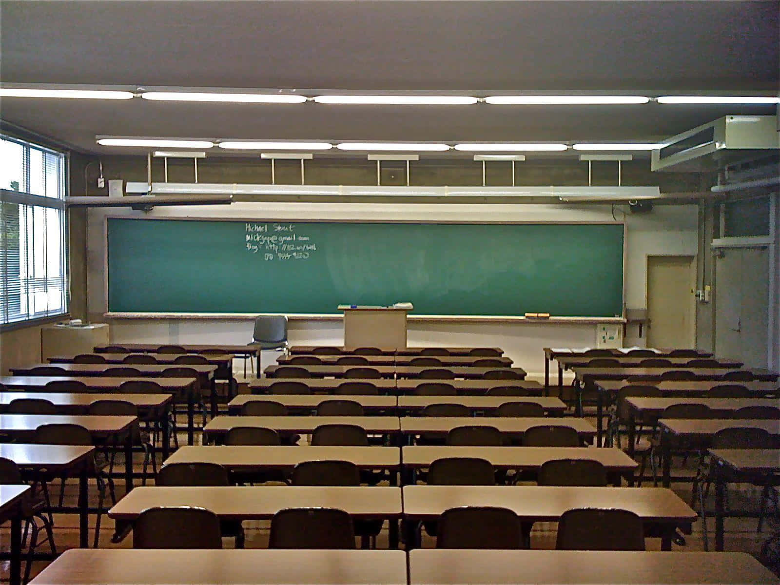 準備 Real Classroom 壁紙 — 空無一人的教室，木製書桌和椅子排成行，面向綠色黑板，上方是螢光燈。