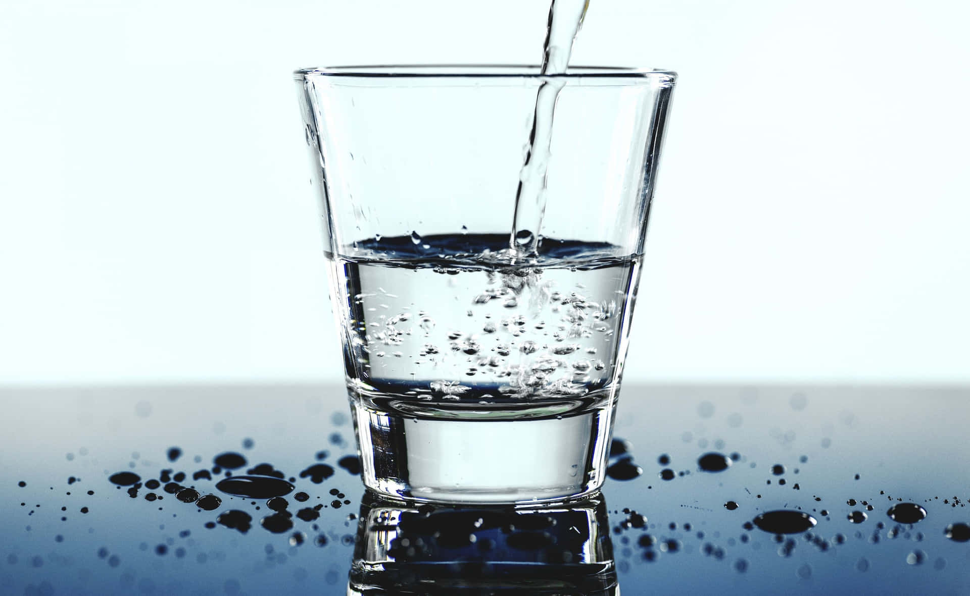 水倒入玻璃杯中，在反射表面上產生氣泡和水滴。