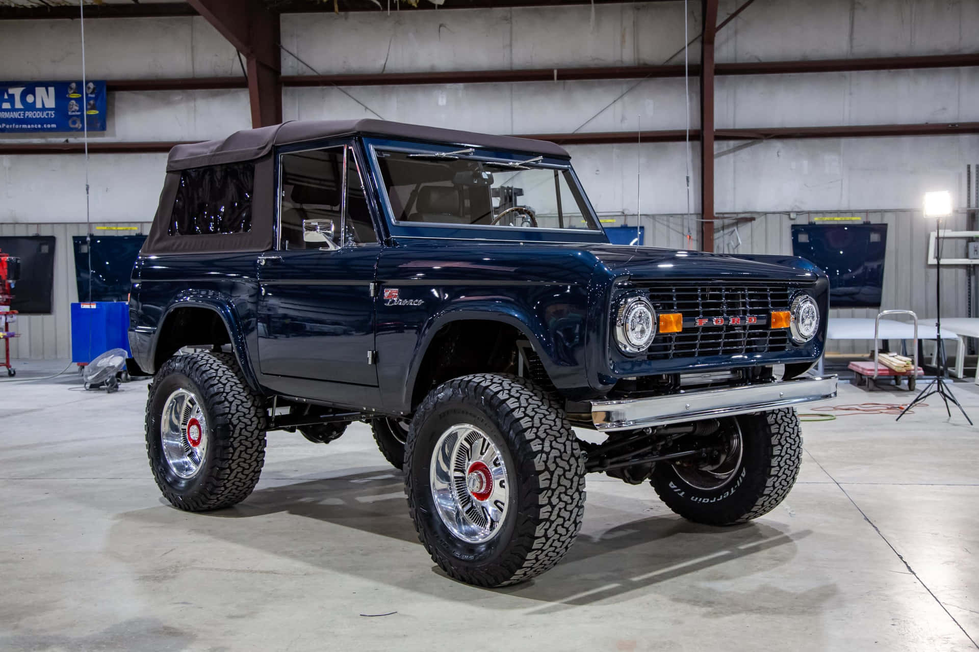 車庫工場中，一輛光澤藍色經典福特Bronco，配備鍍鉻車輪。