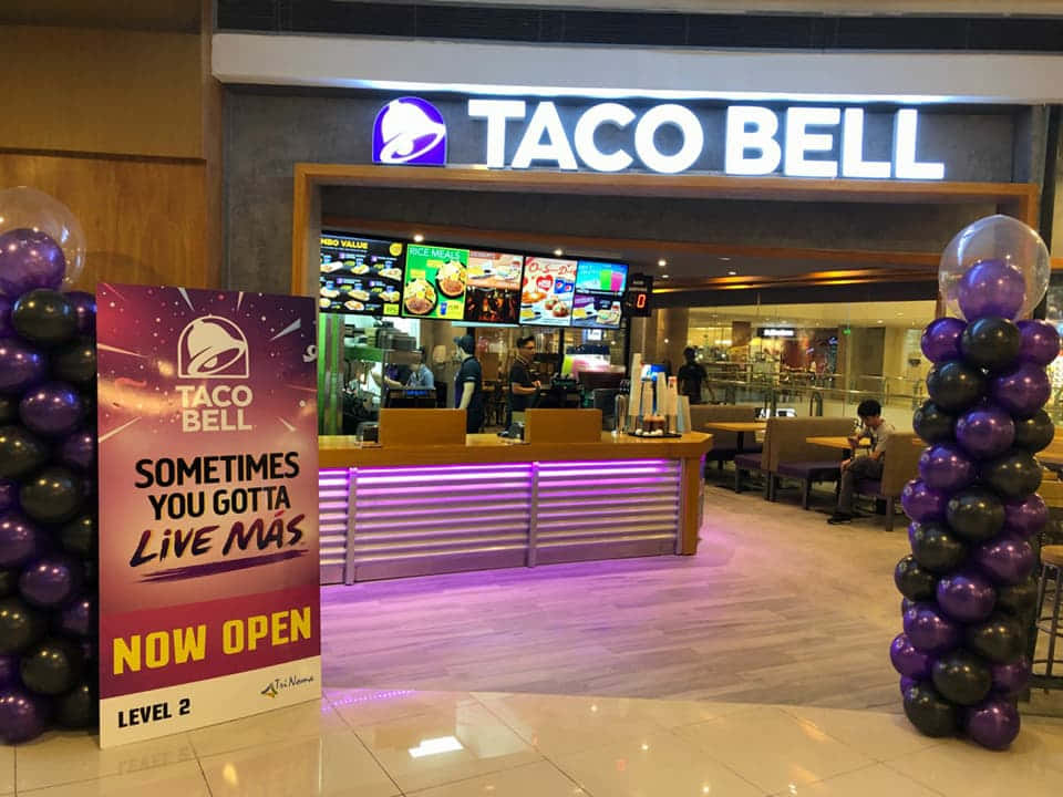 Taco Bell餐廳入口，設有紫色和黑色氣球柱及現已開業標誌。