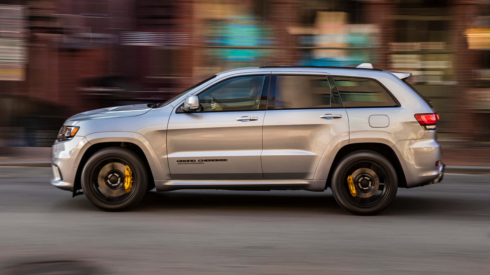 銀色Jeep Grand Cherokee帶動態模糊效果在城市中飛馳。