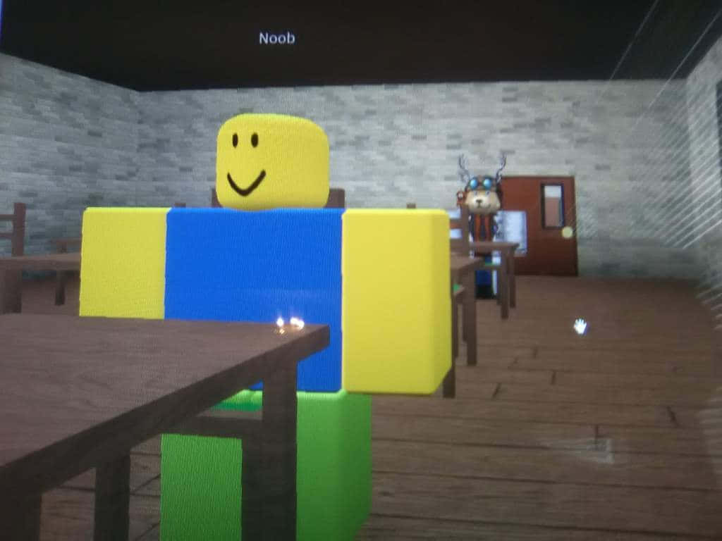 準備好玩樂的Roblox新手 壁紙 — 一個方塊狀的黃藍色頭像，面帶微笑，坐在一張木桌旁，房間光線昏暗，有磚牆，背景中還有另一個角色。
