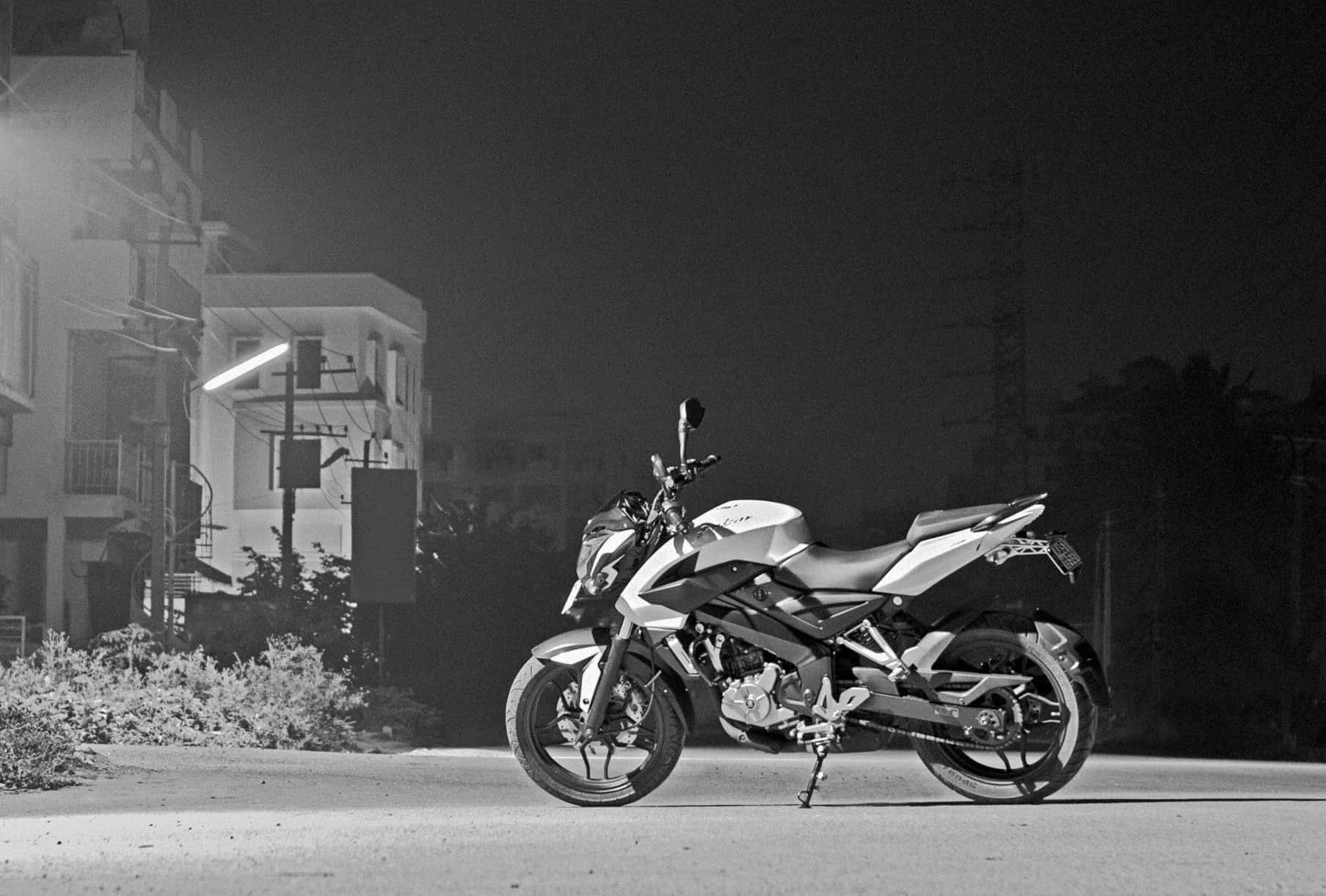 一架電單車在夜間停泊在街道上，背景有建築物。