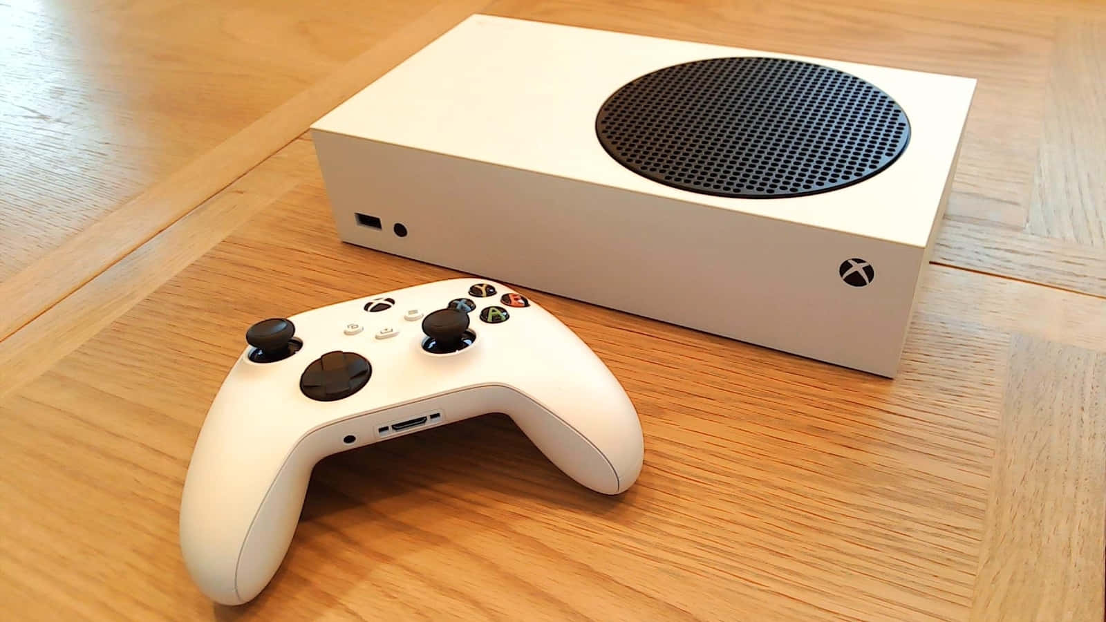 白色Xbox主機及手掣在木地板上