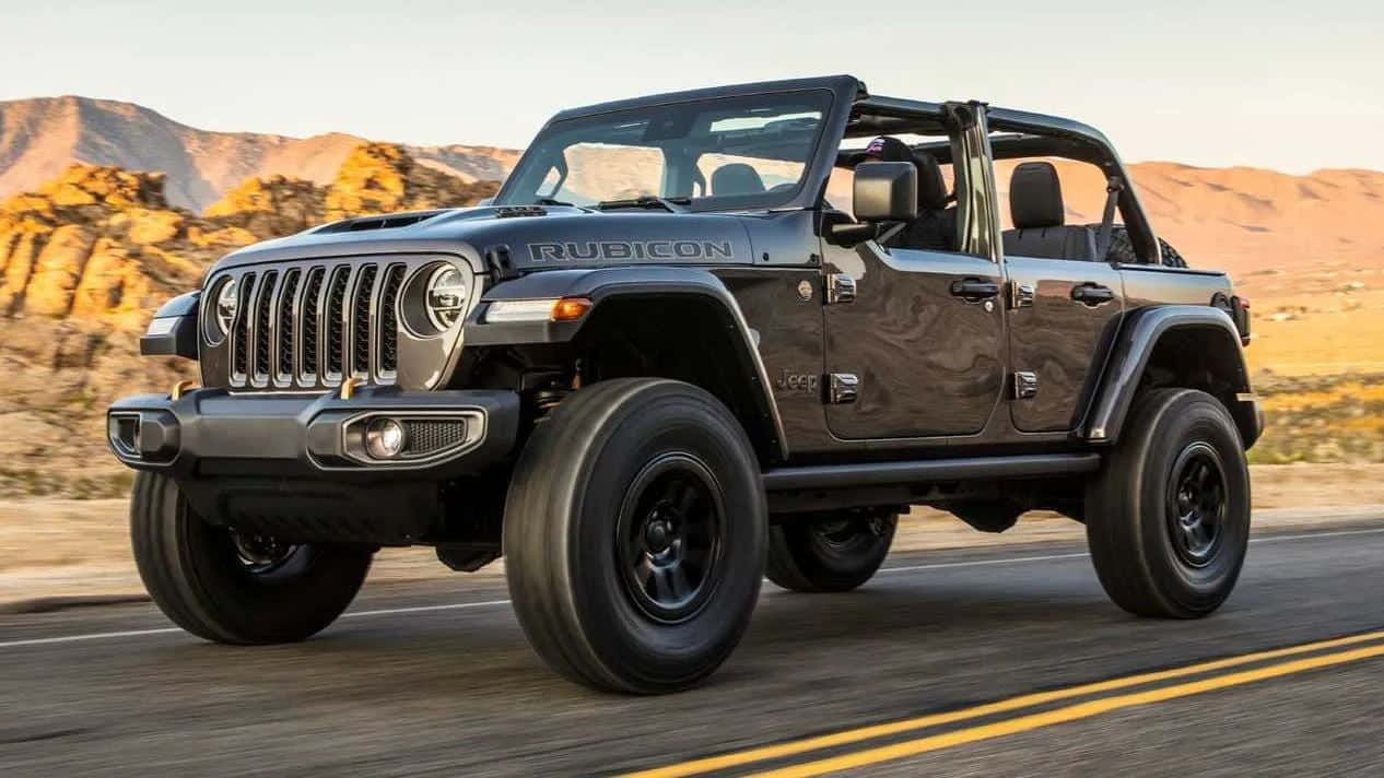 日落時分黑色Jeep Rubicon在沙漠道路上行駛
