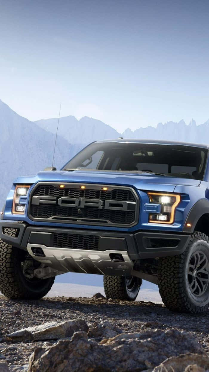 黃昏時分，藍色福特Raptor貨車在岩石山地地形上。