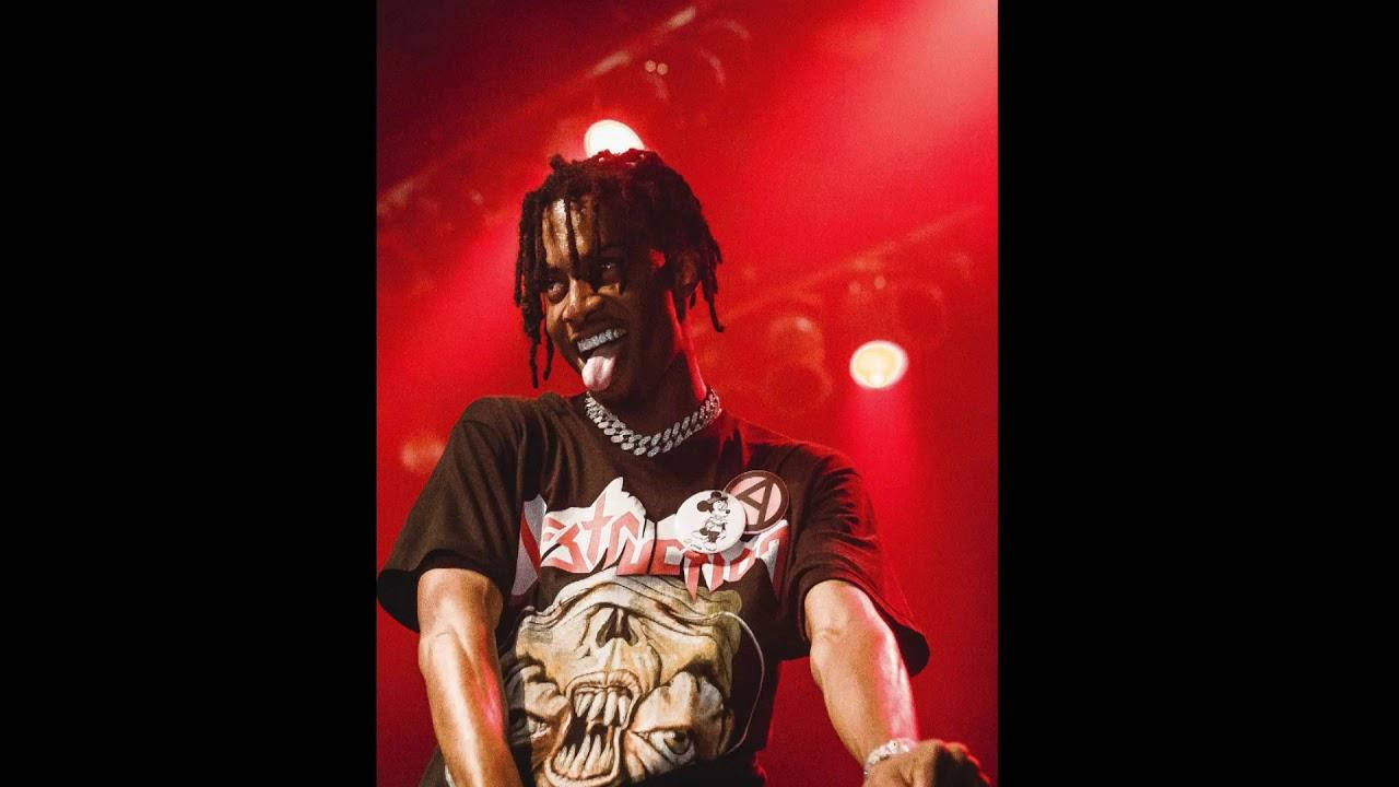 舞台上音樂家在紅光下伸出舌頭，身穿圖案T恤。