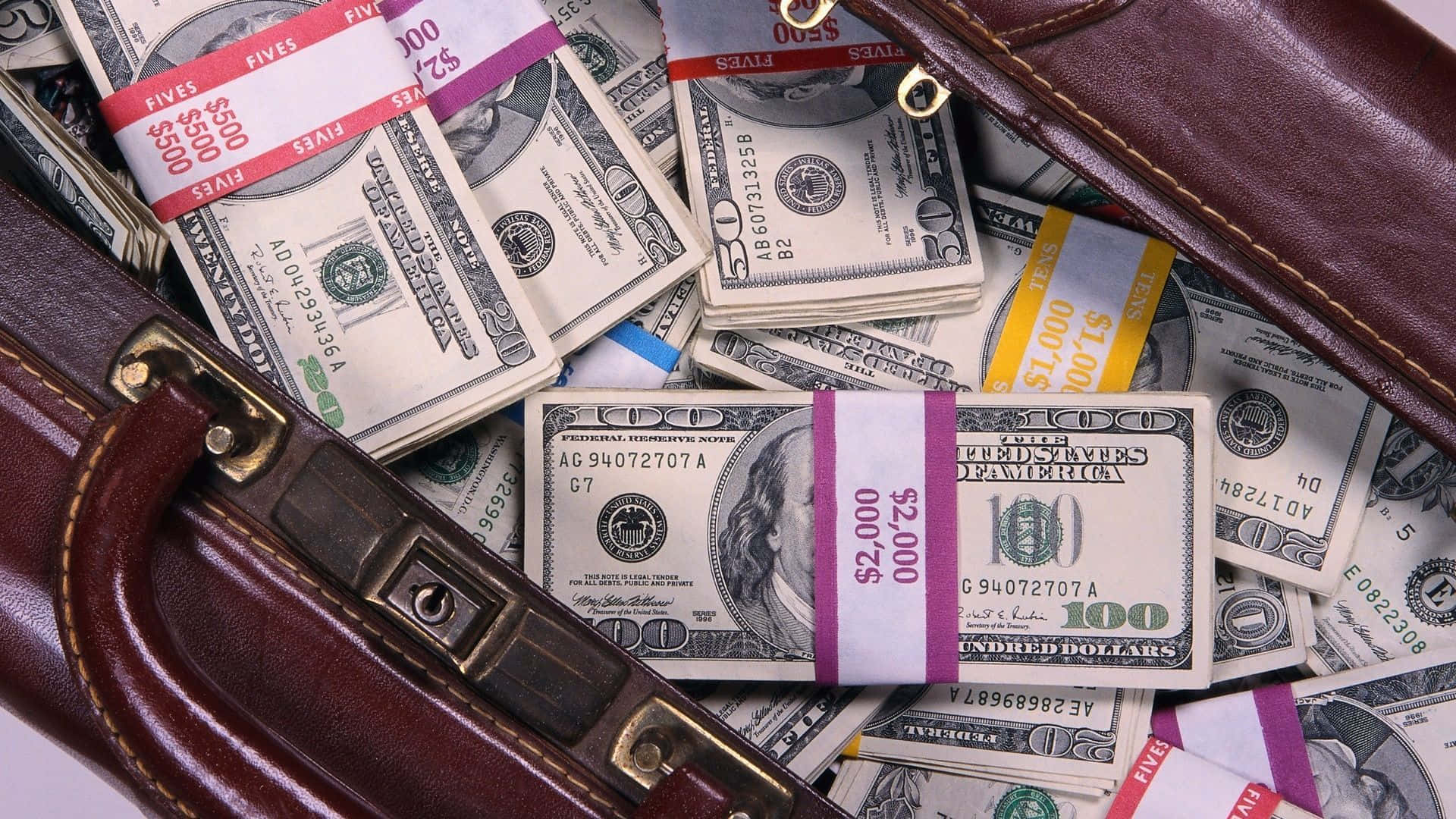 打開的棕色皮革公文包，裝滿了各種面額的美鈔。