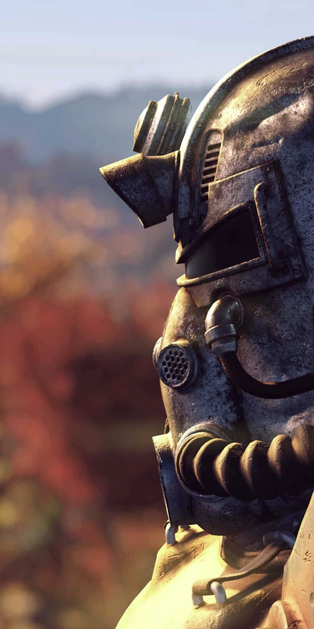 準備用 Pixel 3 探索 Fallout 76 的廢土 壁紙 — 特寫一個風化的動力裝甲頭盔，背景是模糊的秋日森林。