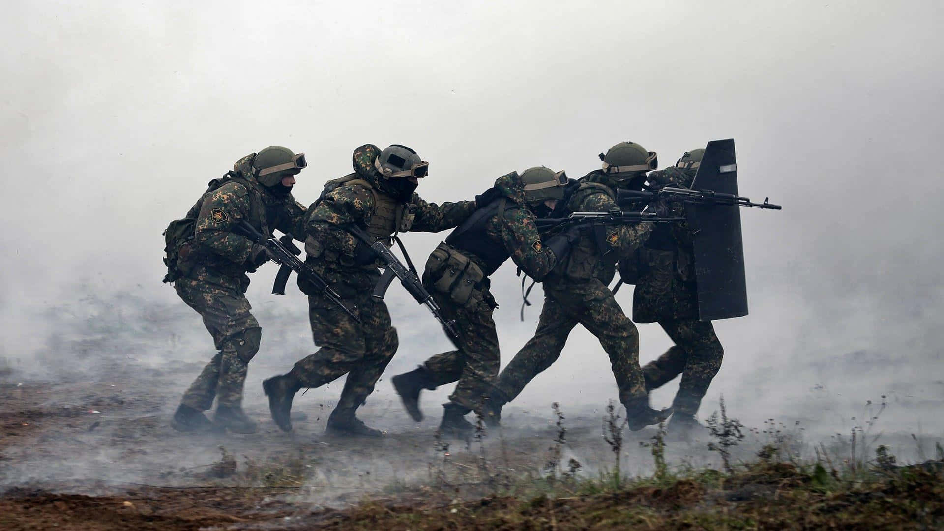 身穿戰鬥裝備的士兵在煙霧中手持步槍和盾牌移動。