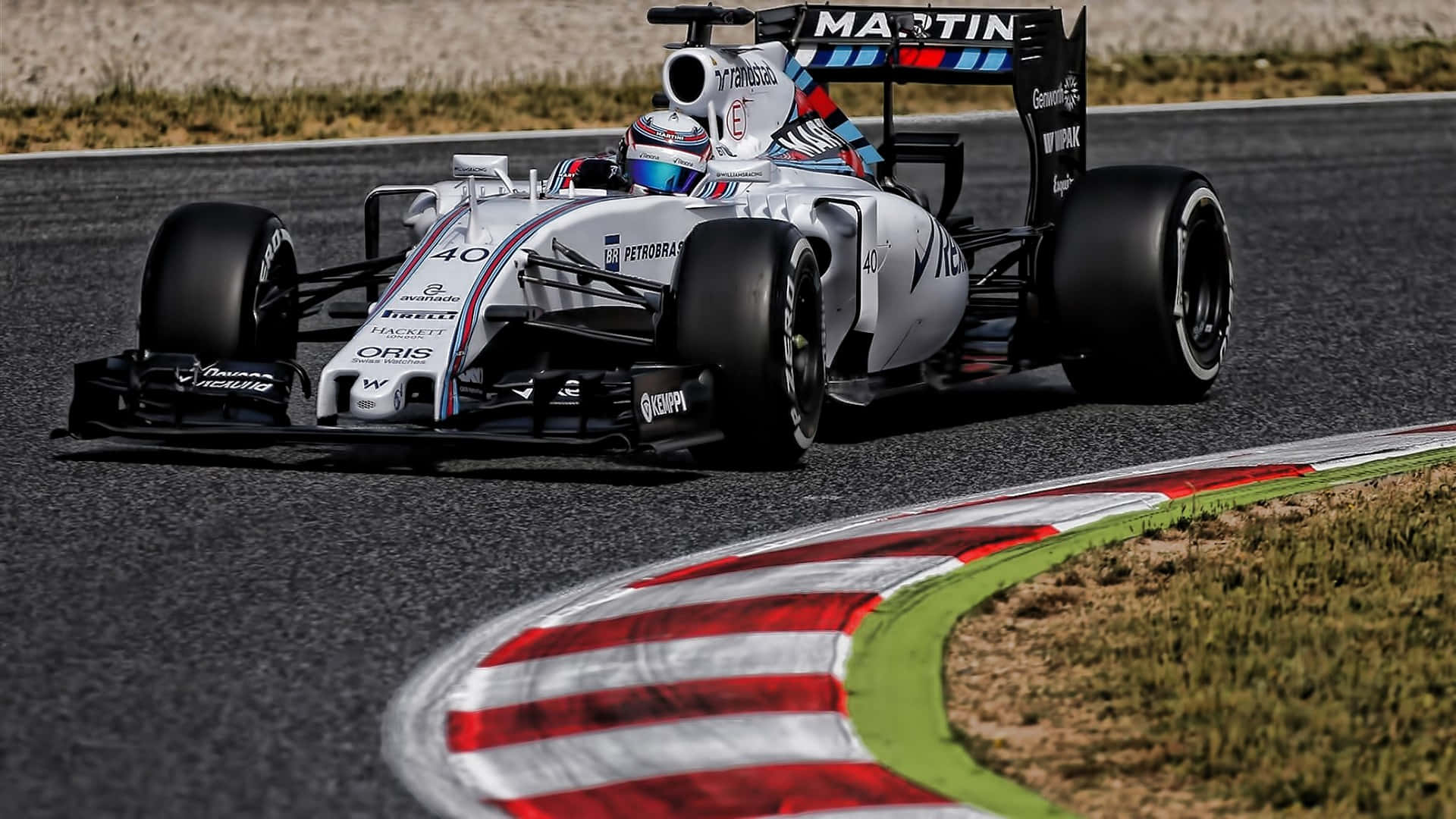 準備迎接 2016 年精彩 F1 賽事 壁紙 — 一架白色和藍色的 Formula 1 賽車，號碼 40，在陽光明媚的賽道上緊貼著紅白綠三色路肩的彎道飛馳。