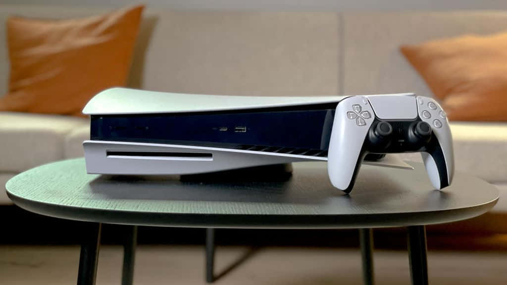 白色PlayStation 5主機和手掣放在玻璃桌上，靠近帶橙色枕頭的米色梳化。