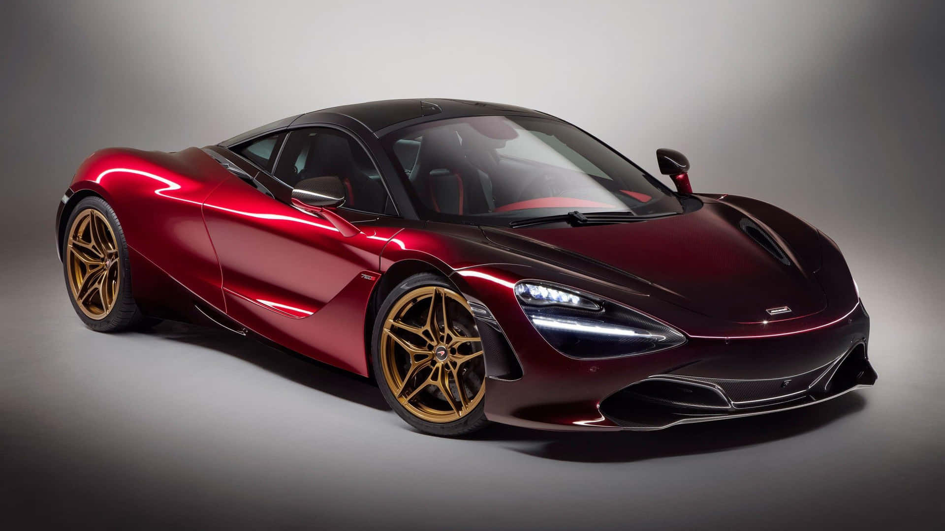 酒紅色McLaren 720S跑車配金色輪圈在攝影棚燈光下。