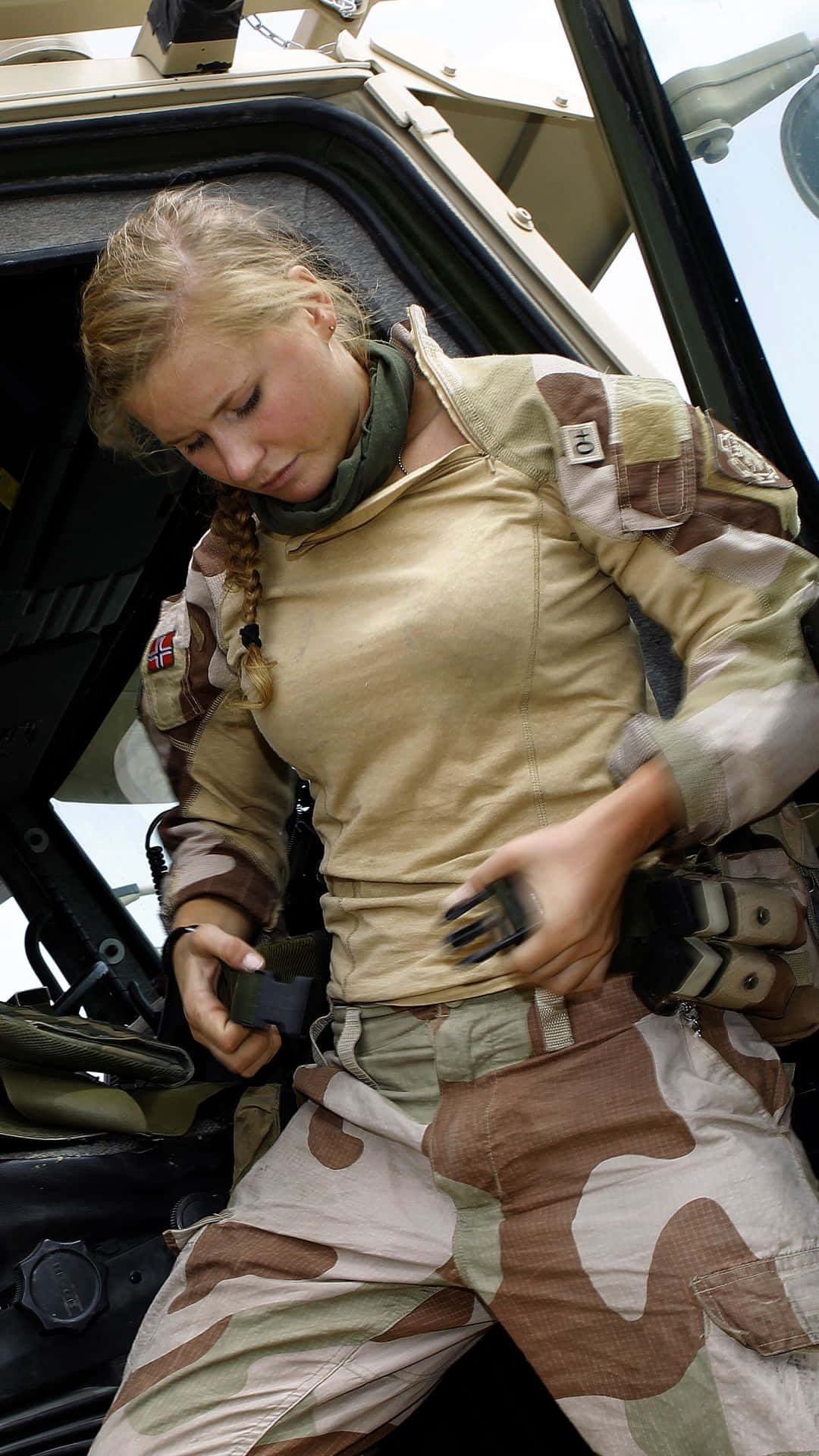 身穿迷彩制服的女兵在軍車內調整裝備