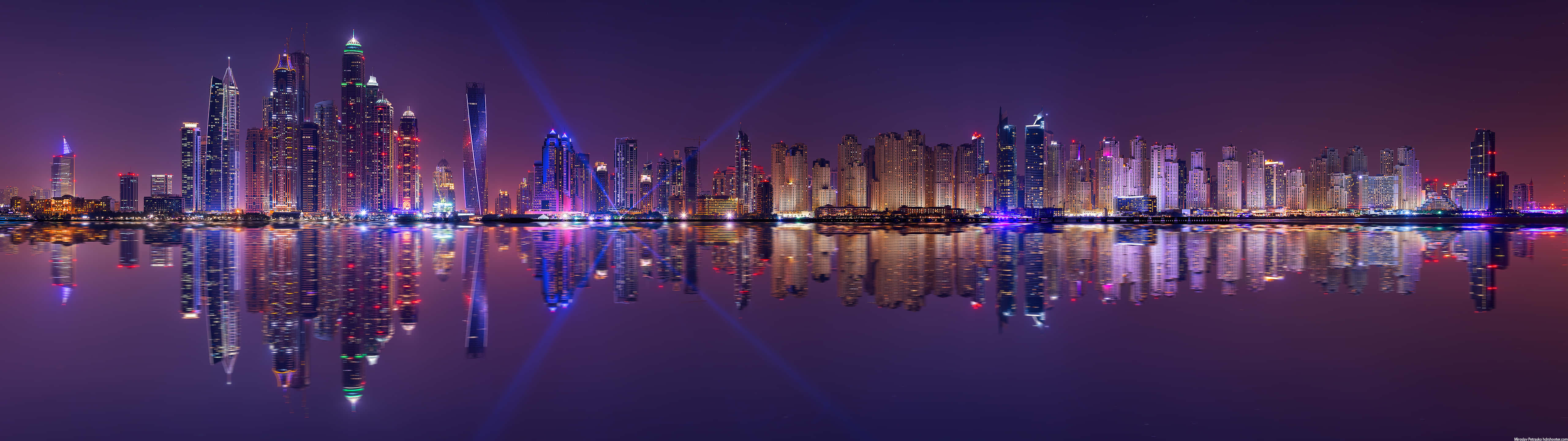 未來城市天際線夜景，色彩繽紛的燈光倒映在水中。