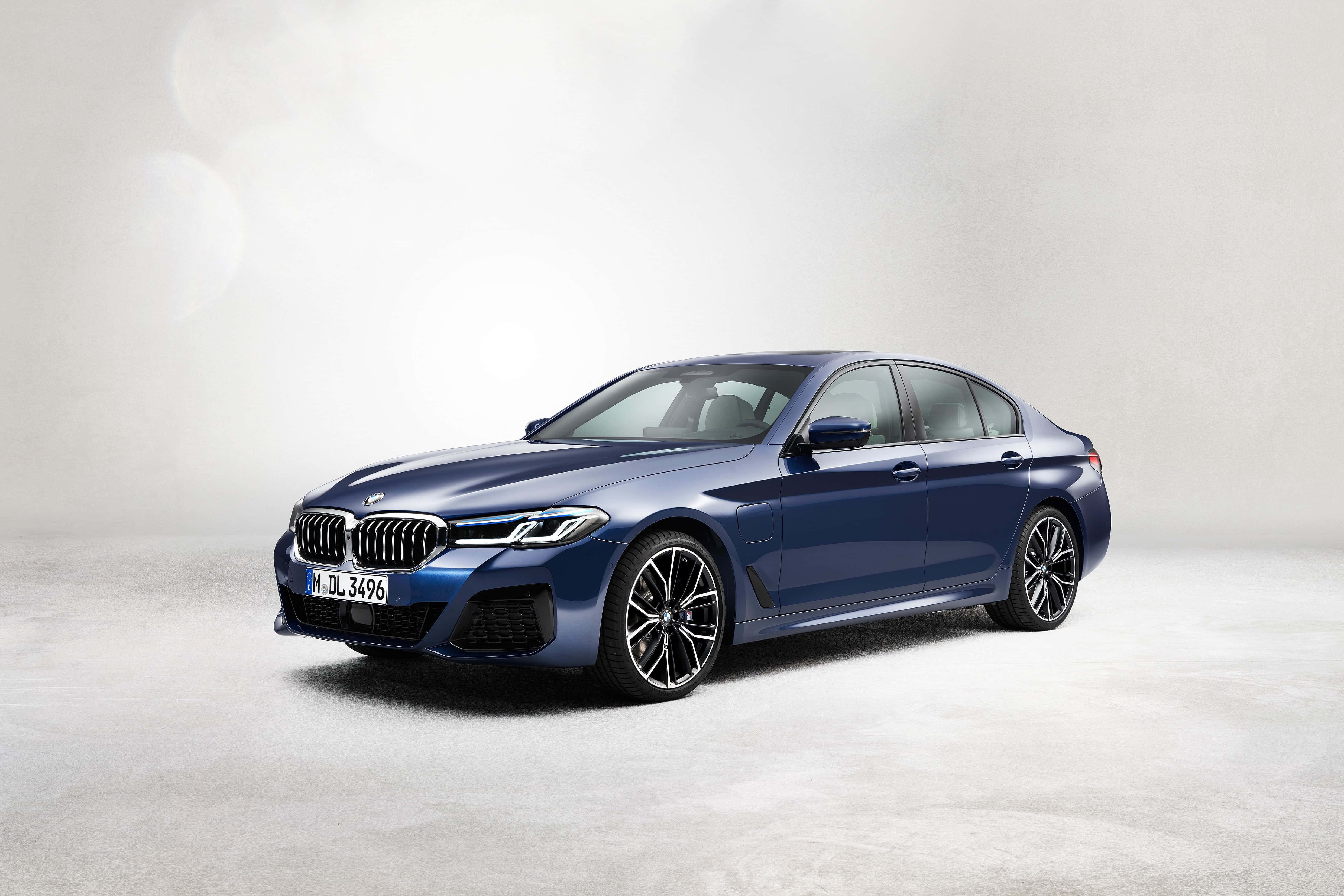 準備駕馭城市與賽道——BMW M Sport 壁紙 — 一部時尚的藍色寶馬5系轎車在柔和的工作室燈光下，在簡約的灰色背景前閃閃發光。