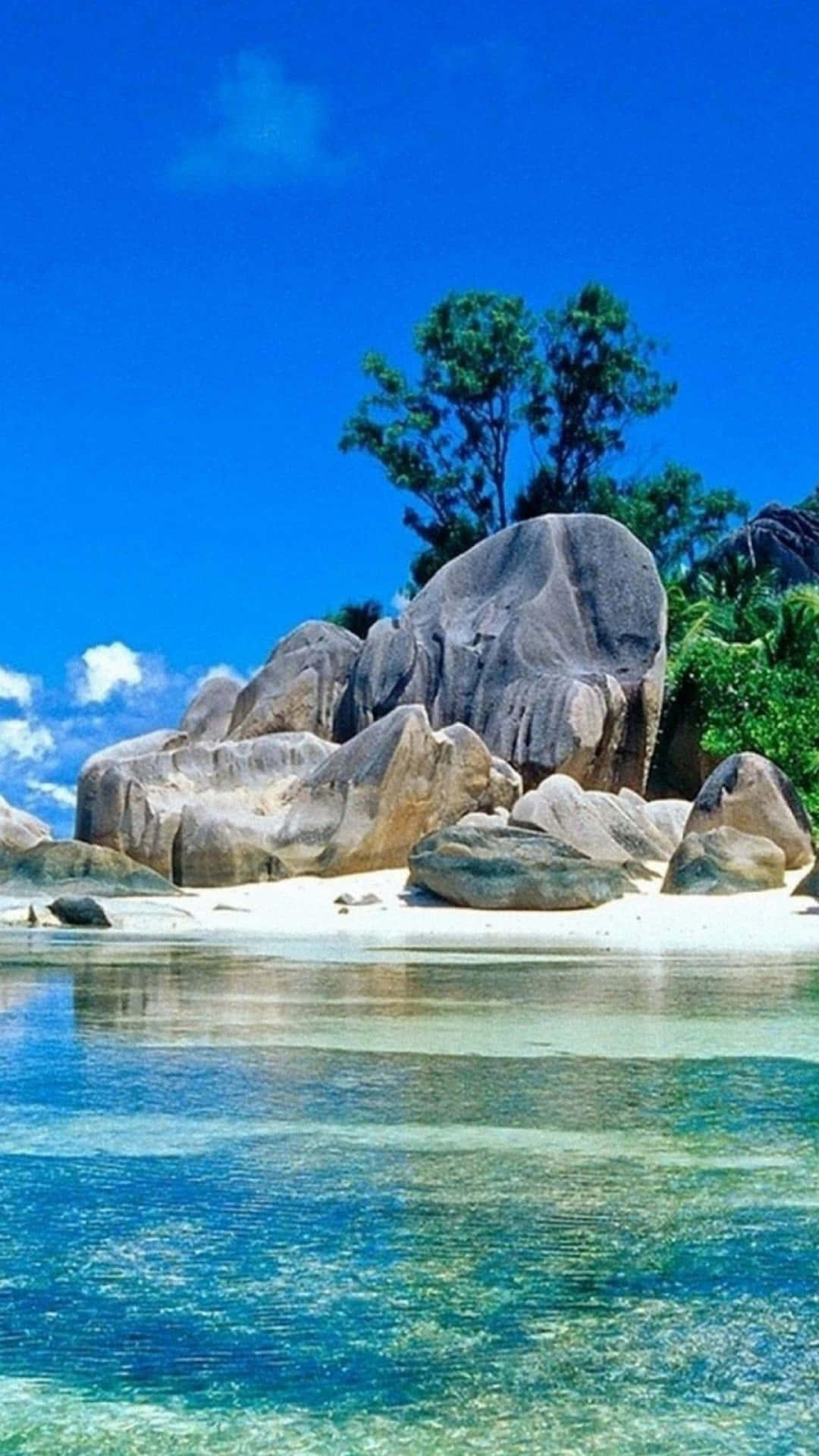 熱帶海灘，有碧綠的海水和巨大的岩石，在明亮的藍天下。