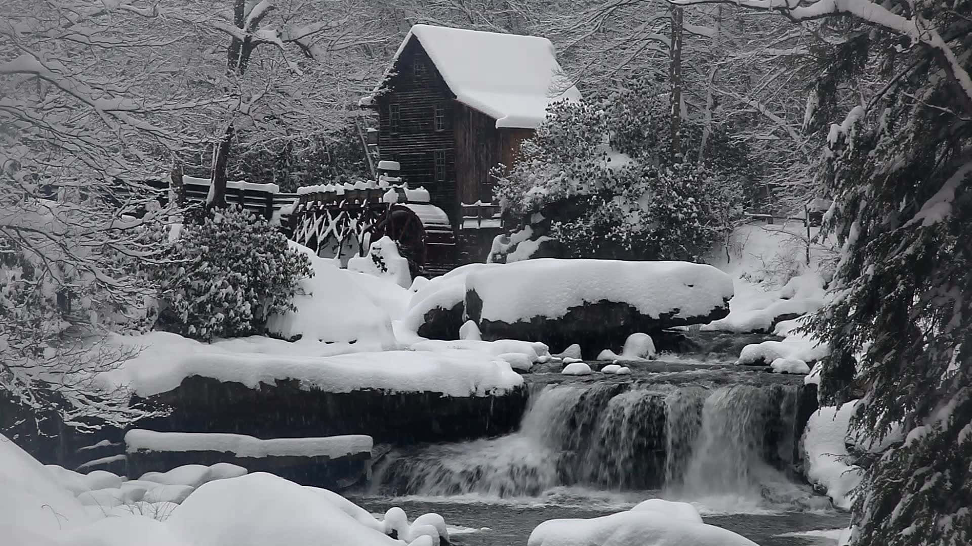 被雪覆蓋的木製水車磨坊，冬季森林溪流旁