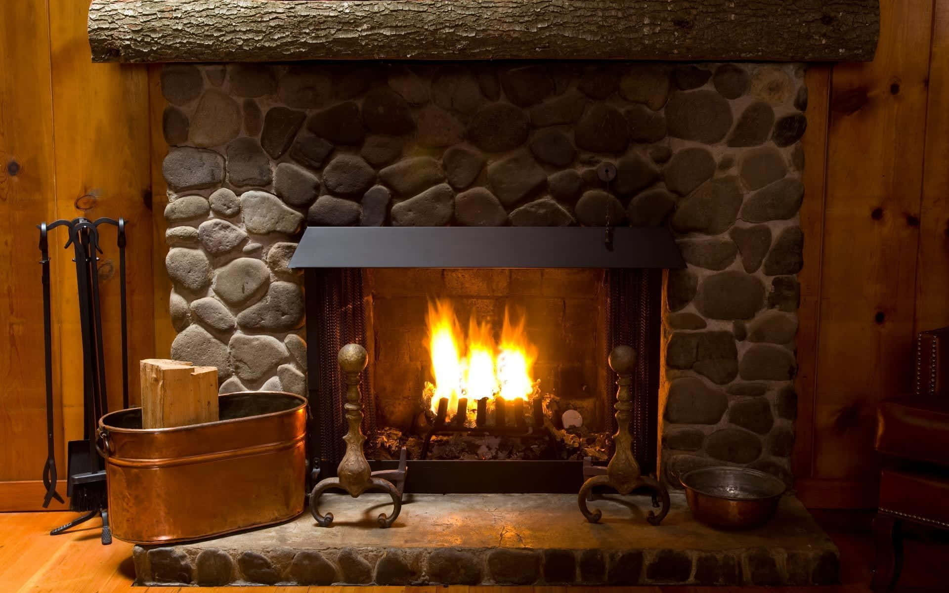 Autumn Fireplace 桌布 壁紙 — 溫暖的火焰在質樸的石砌壁爐中熊熊燃燒，周圍是木牆和銅製壁爐工具。