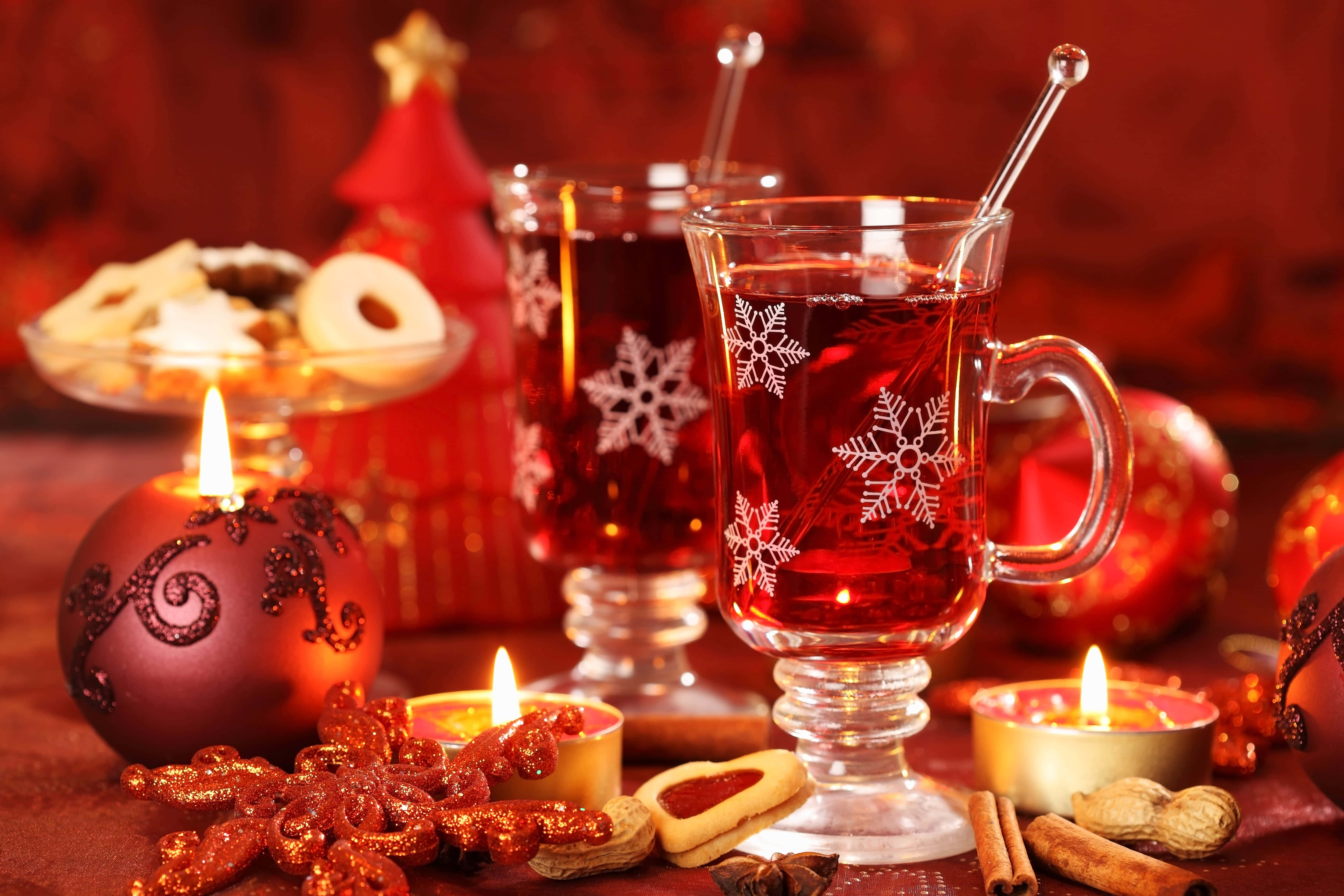 Mulled Wine 桌布 壁紙 — 溫暖的紅酒在雪花馬克杯中，在點燃的蠟燭和節日餅乾旁，在濃郁的紅色桌布上閃耀。