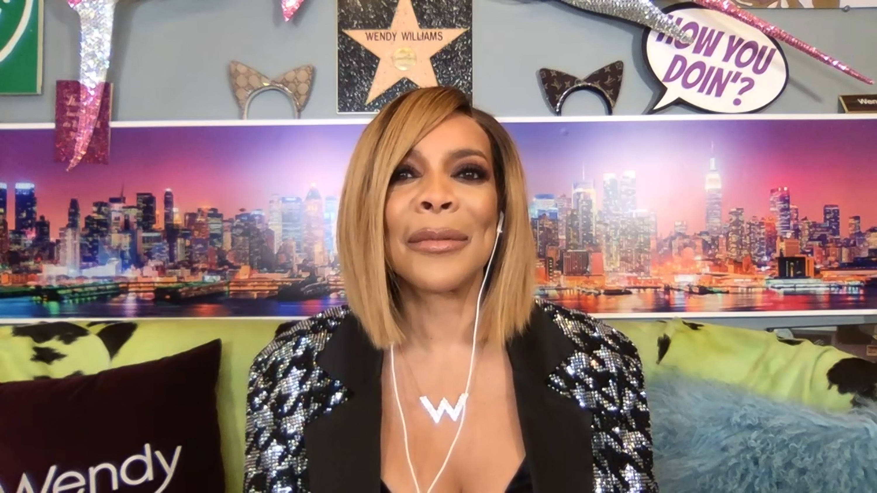 溫迪·威廉姆斯直播 壁紙 — Wendy Williams 穿著閃亮西裝外套，在充滿活力的紐約天際線背景下微笑，搭配閃亮裝飾。