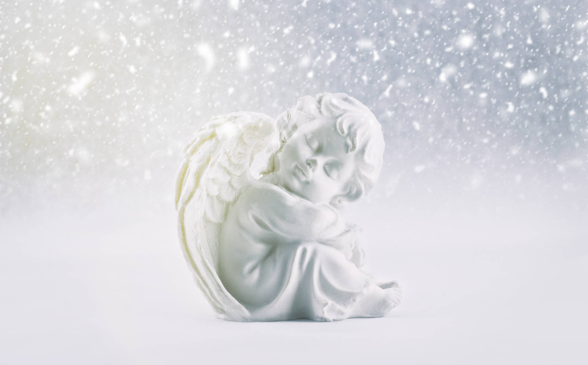 一座白色大理石天使雕像在飄雪下蜷縮入睡。