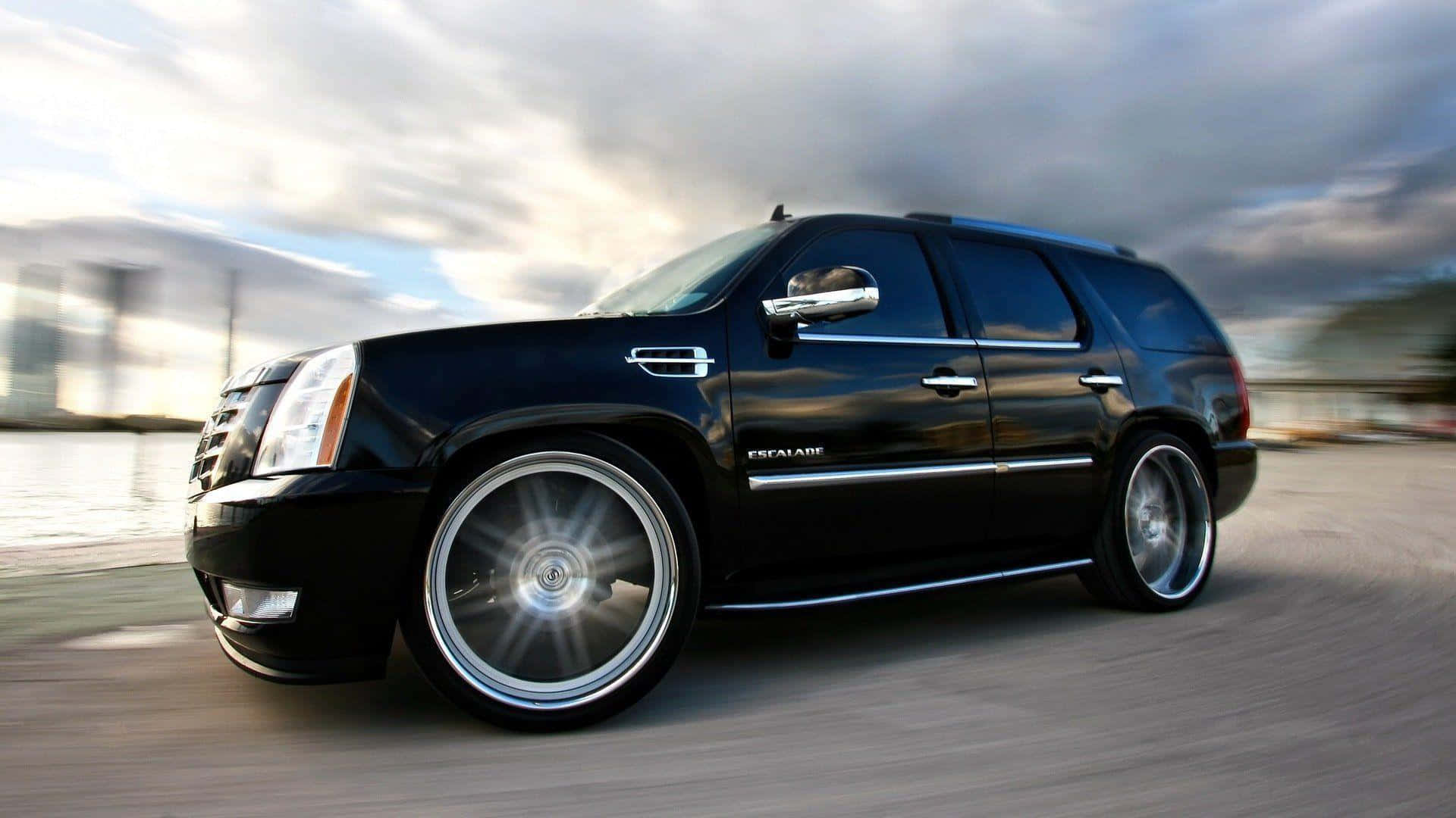 黑色Cadillac Escalade SUV在海濱道路上飛馳，帶有動態模糊效果。