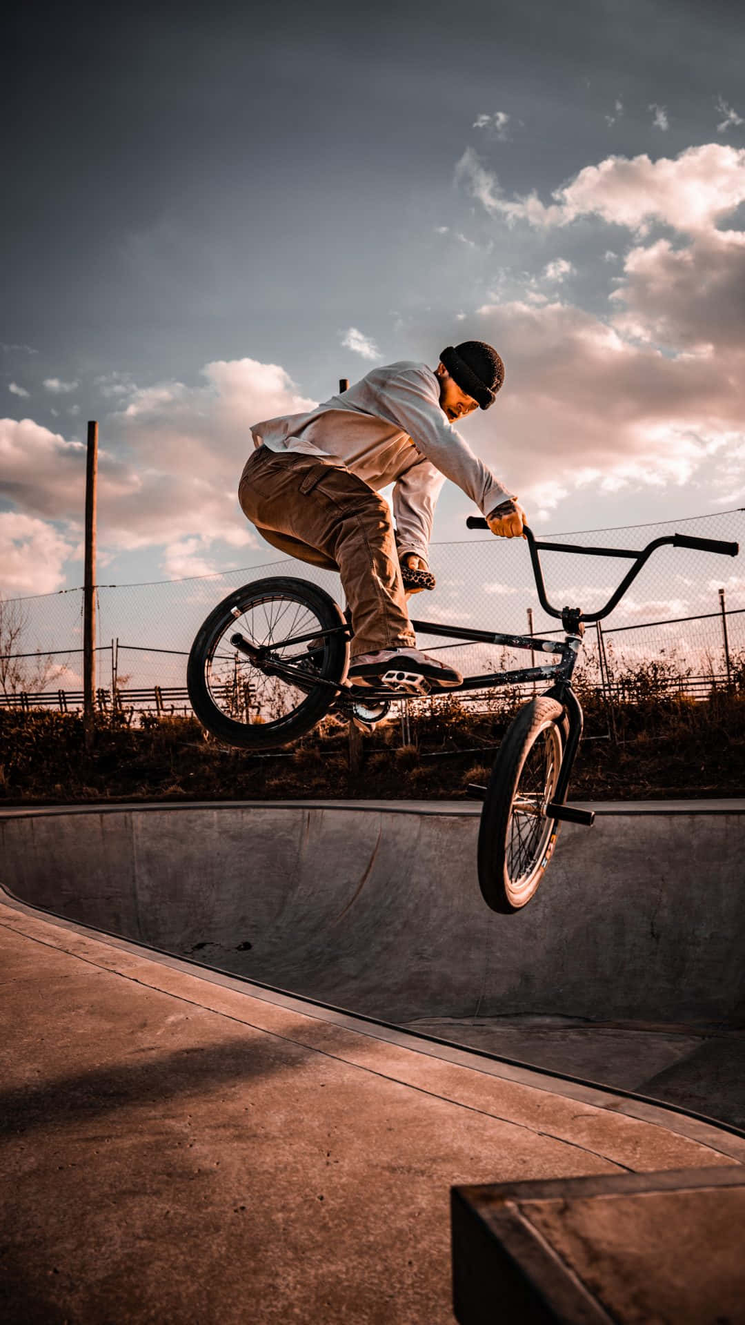 BMX車手在日落時分在混凝土滑板碗池中表演特技。