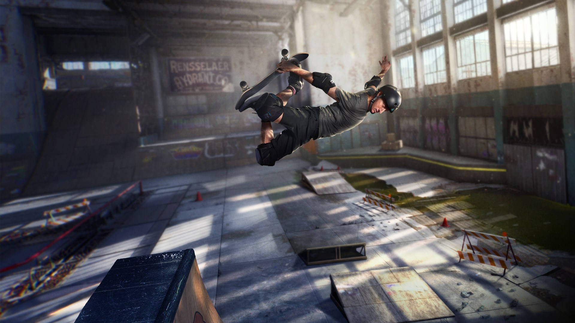滑板少年 Tony Hawk's Pro Skater 壁紙 — 一名滑板手在半空中，於陽光照射的廢棄倉庫滑板場表演技巧。