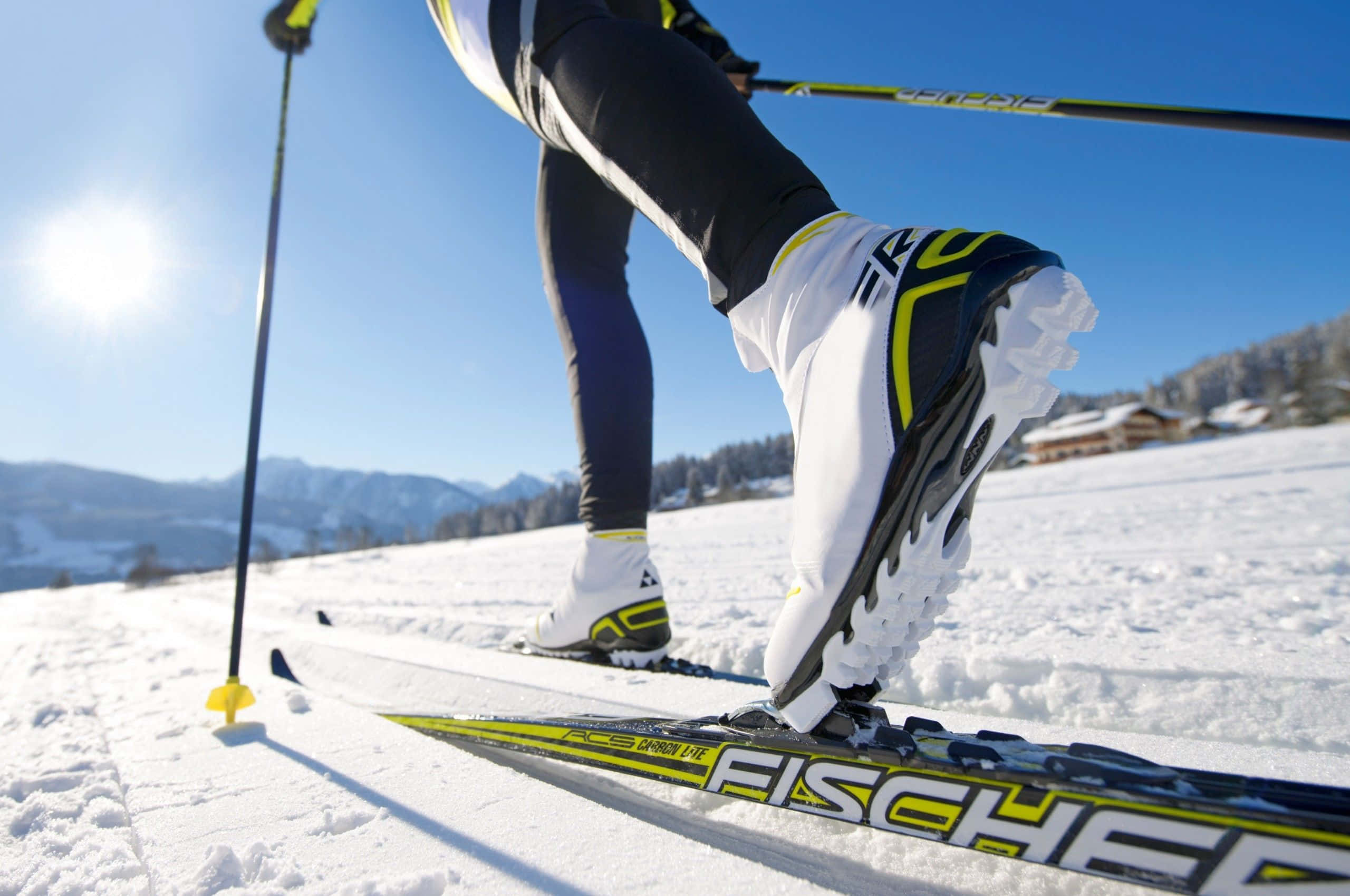Winter Sports 桌布 壁紙 — 滑雪者靴子和滑雪板在陽光普照的雪地上特寫，背景為山巒。