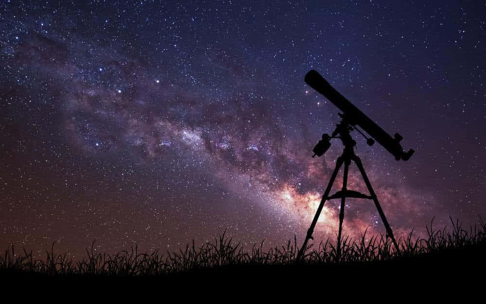 「滿天繁星的夜空」 壁紙 — 草地上望遠鏡的剪影，指向在繁星點點的夜空中閃耀的銀河系。
