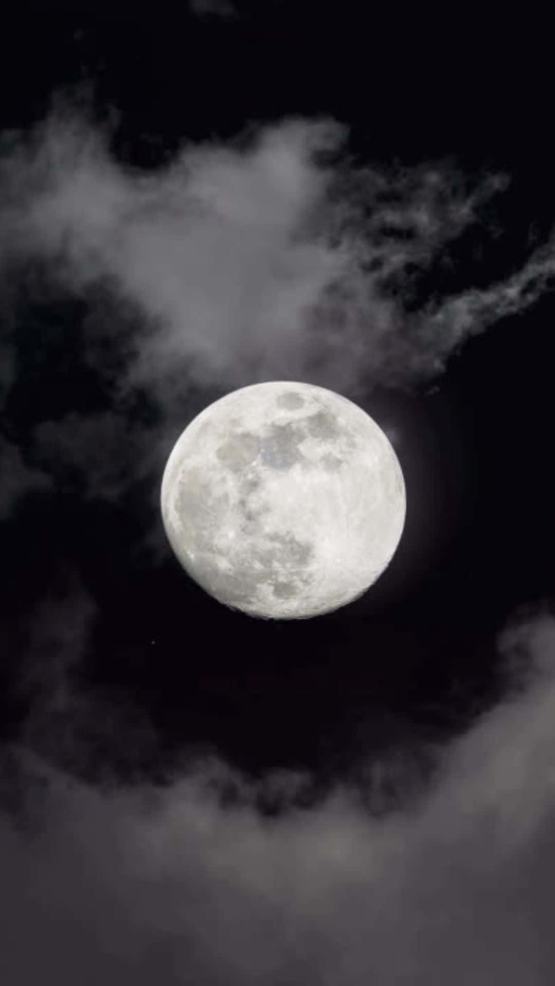 滿月透過飄動的雲層在黑暗的夜空中閃耀