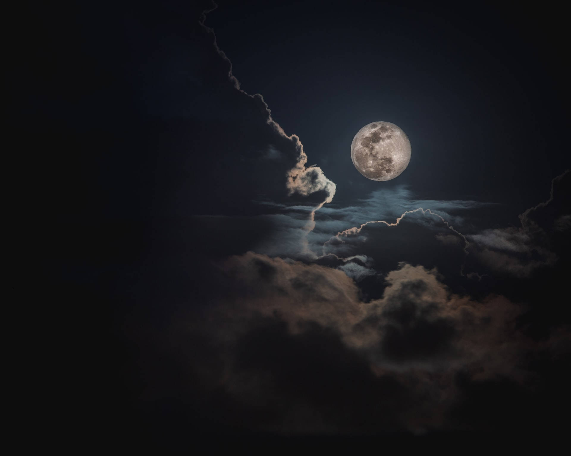滿月在夜間穿過黑暗的暴風雲閃耀。