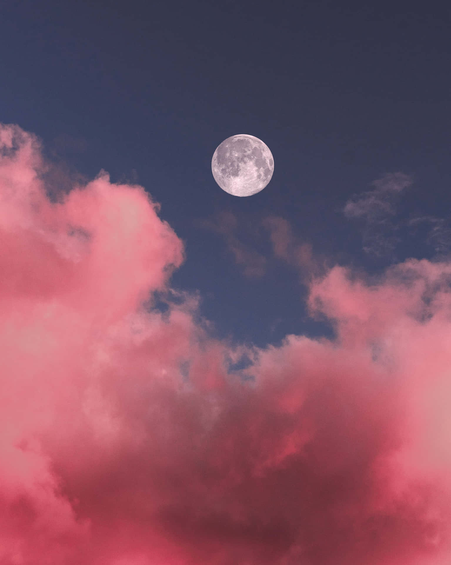 滿月在深藍色夜空中從粉紅色雲朵上方升起。
