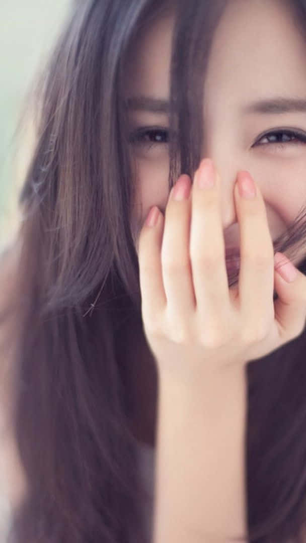 一位微笑的女子俏皮地用手遮住嘴巴。