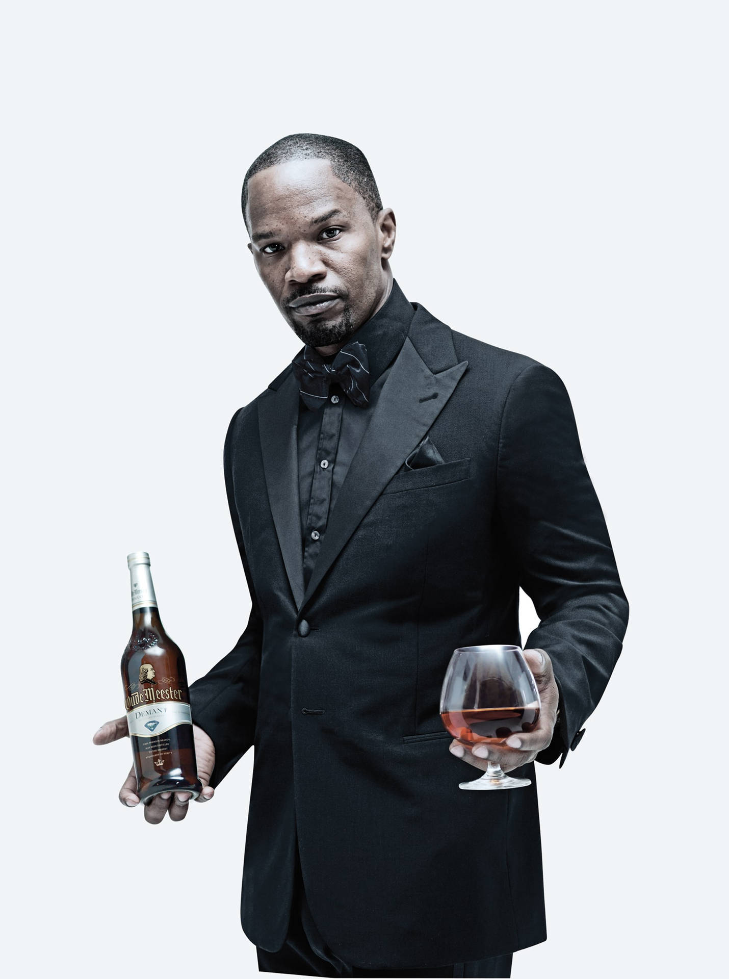 穿黑色燕尾服的男人拿著威士忌酒瓶和酒杯。