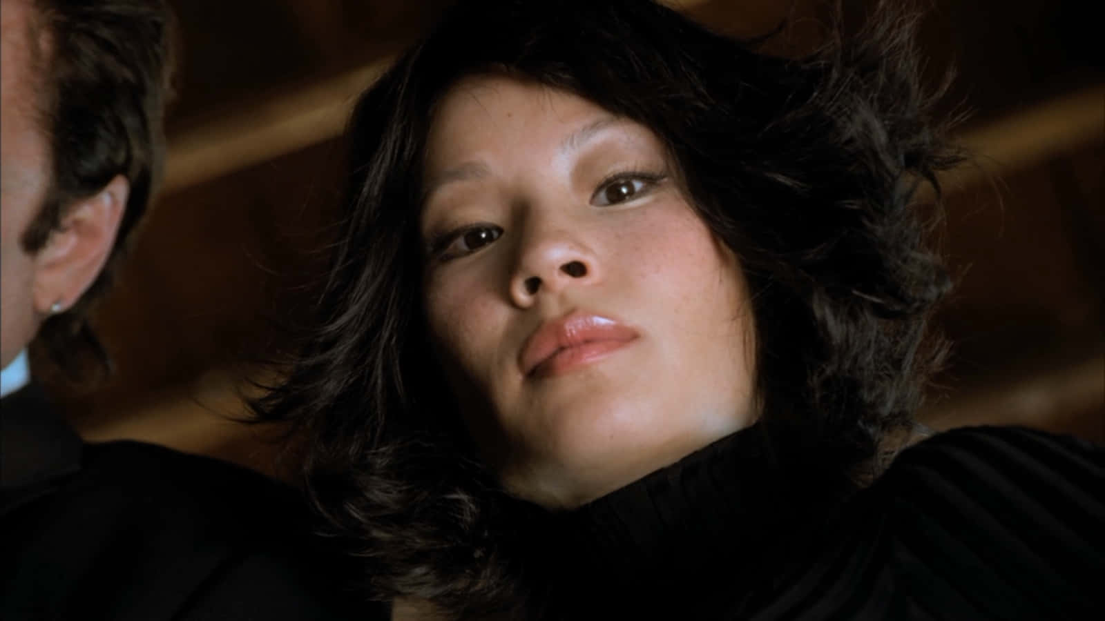 一個深色頭髮的女人在昏暗的房間裡向上看。