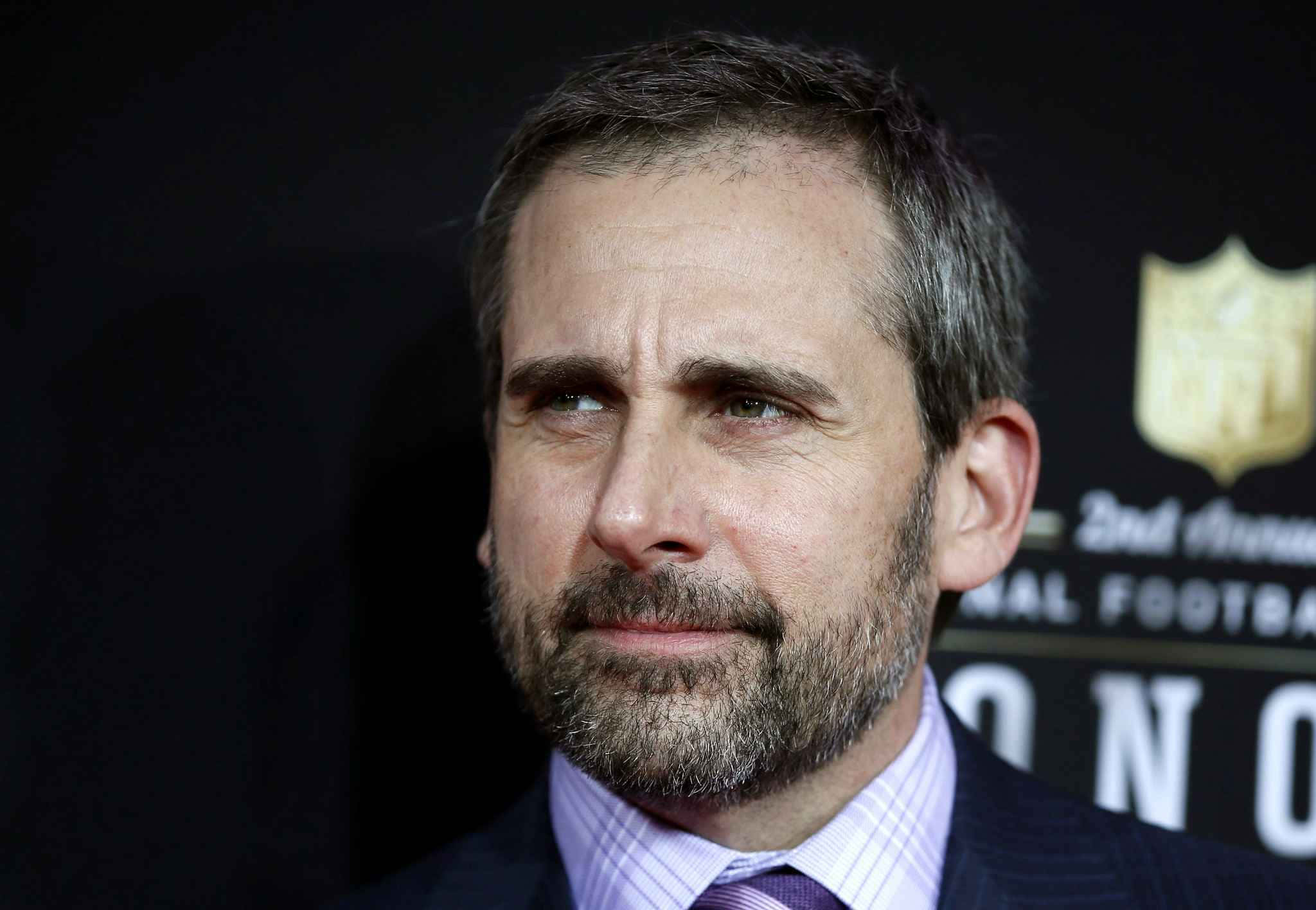 steve carell 桌布 壁紙 — 演員史提夫加維身穿西裝在NFL活動中嚴肅地望向鏡頭外的特寫肖像。