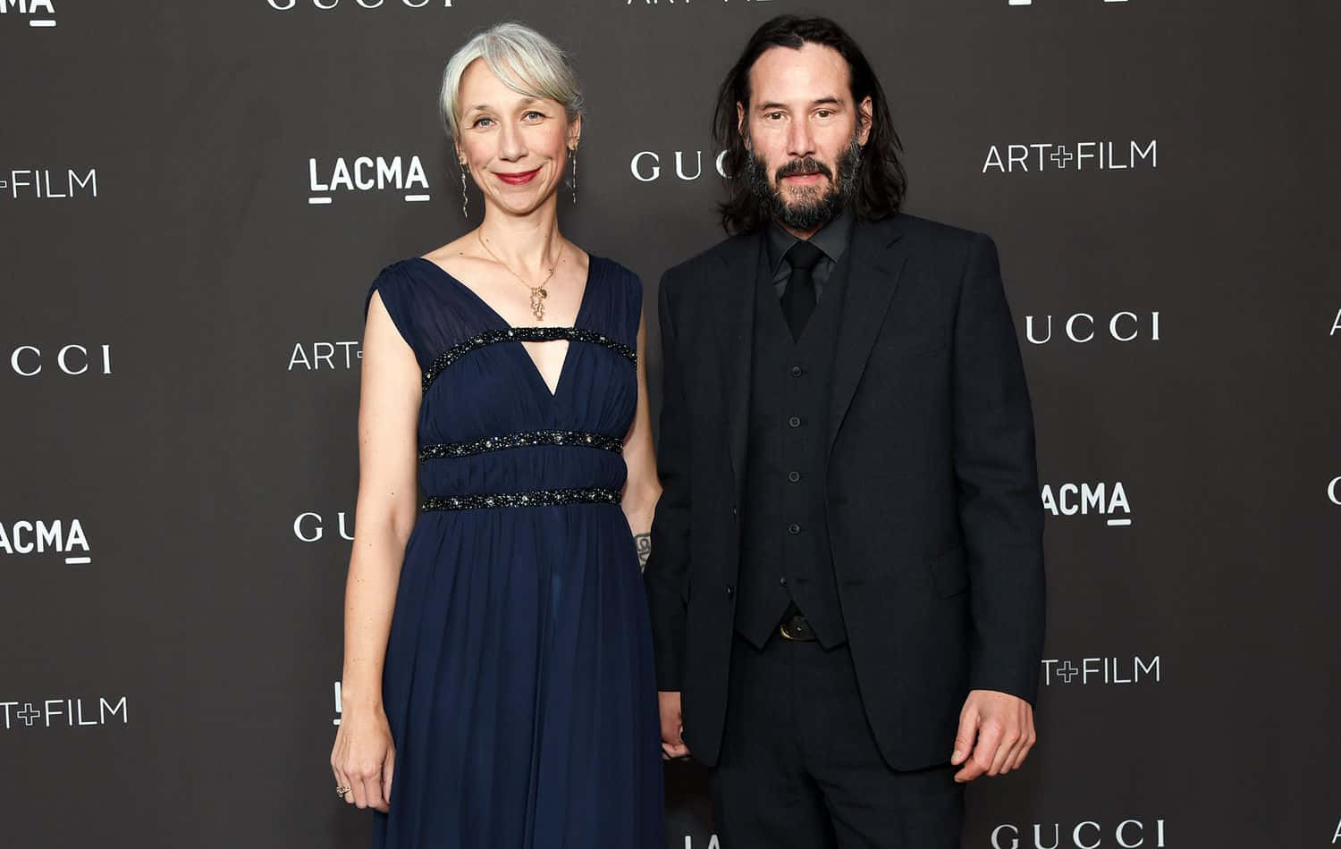 Keanu Reeves 桌布 壁紙 — 演員艾曼紐·麗華和奇洛·李維斯在紅地毯活動中，以品牌背景優雅地擺姿勢。