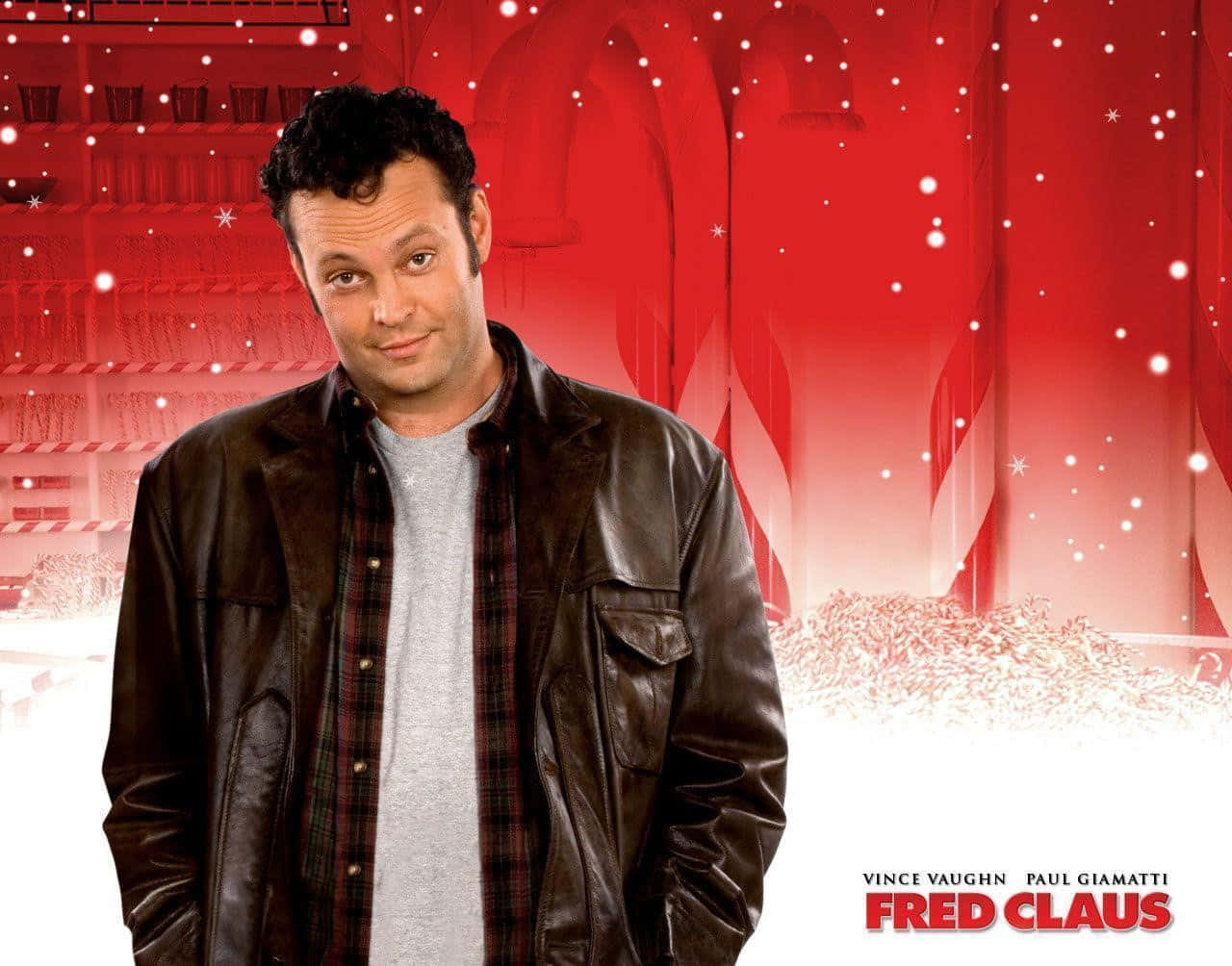 Vince Vaughn 桌布 壁紙 — 演員雲斯·域漢穿著皮褸，在節日紅色糖果棒工廠背景下微笑，雪花飄落。