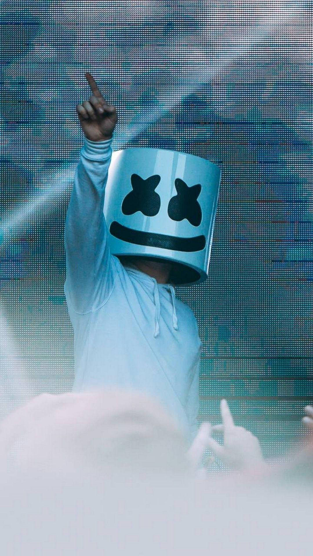 演唱會指向上方Marshmello iPhone壁紙 壁紙 — 一位DJ戴著標誌性的白色頭盔，黑色X眼睛，在發光的數位螢幕背景下向上指。