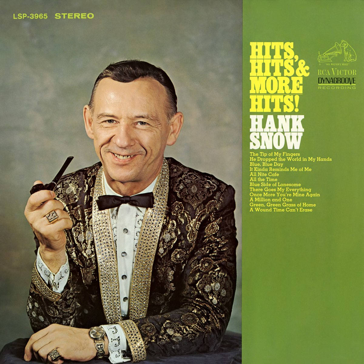 漢克·斯諾《熱門歌曲與更多熱門歌曲》黑膠唱片 壁紙 — Hank Snow 穿著閃亮的黑色和金色西裝，手持煙斗，在柔和的灰色背景前溫暖微笑，旁邊是充滿活力的綠色專輯封套，列出他的熱門歌曲。