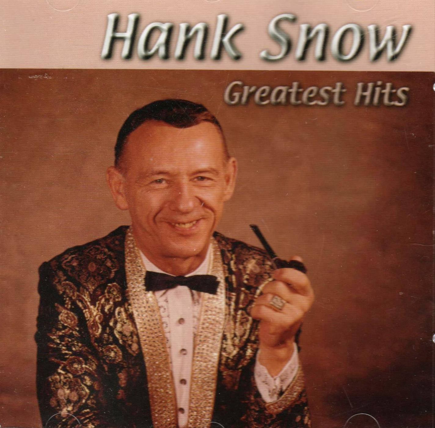 漢克·斯諾經典金曲專輯封面 壁紙 — Hank Snow 穿著閃閃發光的金色和黑色外套，拿著煙斗，在棕色工作室背景前溫暖地微笑。