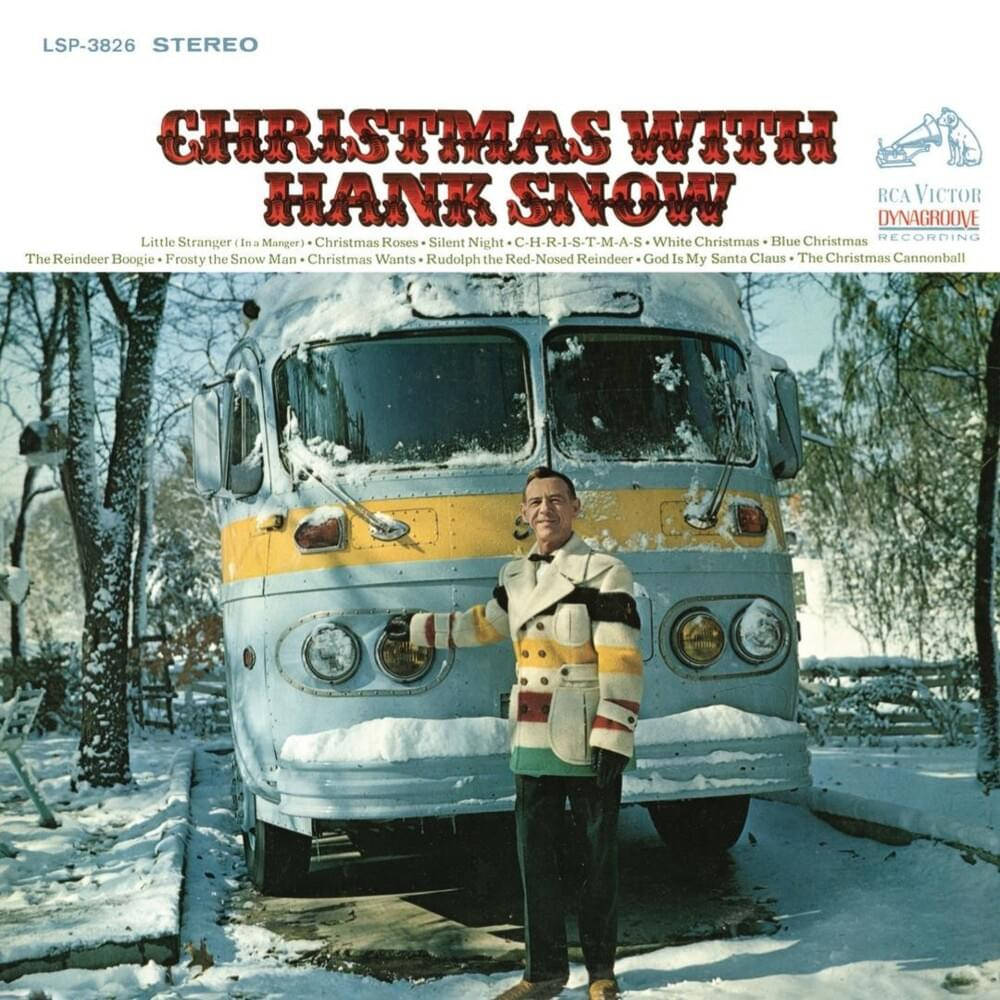漢克·斯諾聖誕專輯 壁紙 — Hank Snow 喺明亮嘅冬日陽光下，企喺一個被雪覆蓋嘅 vintage 巴士旁邊嘅雪地庭院入面微笑。