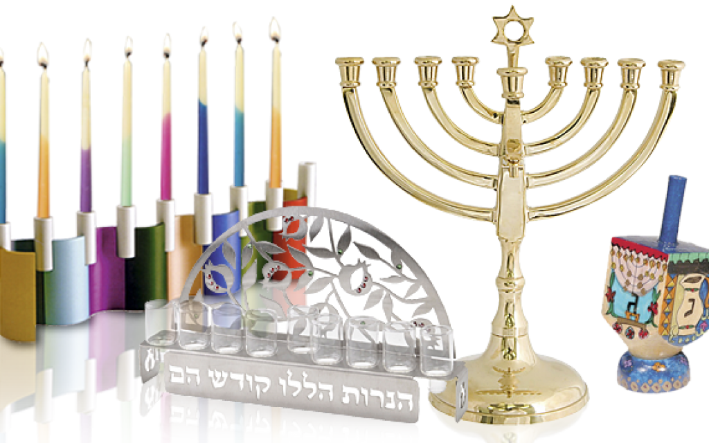 漢克節燭台與陀螺展示 壁紙 — 金色 menorah 上點燃的蠟燭旁邊擺放著彩色蠟燭、dreidel 和裝飾性光明節物品，置於反光表面上。